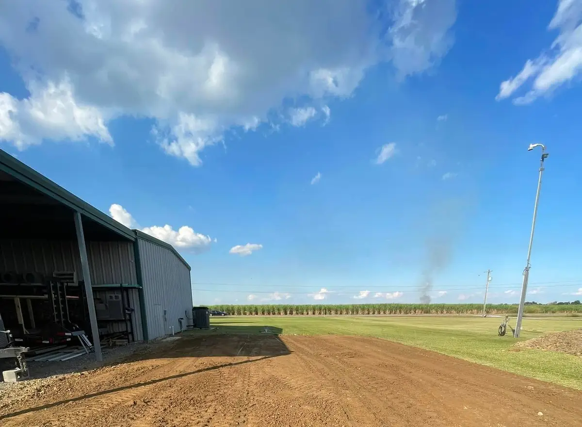 Graded pad beside a shop with a sugarcane field beyond